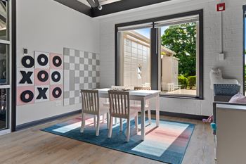 A dining room with a checkered wall and a table with chairs.